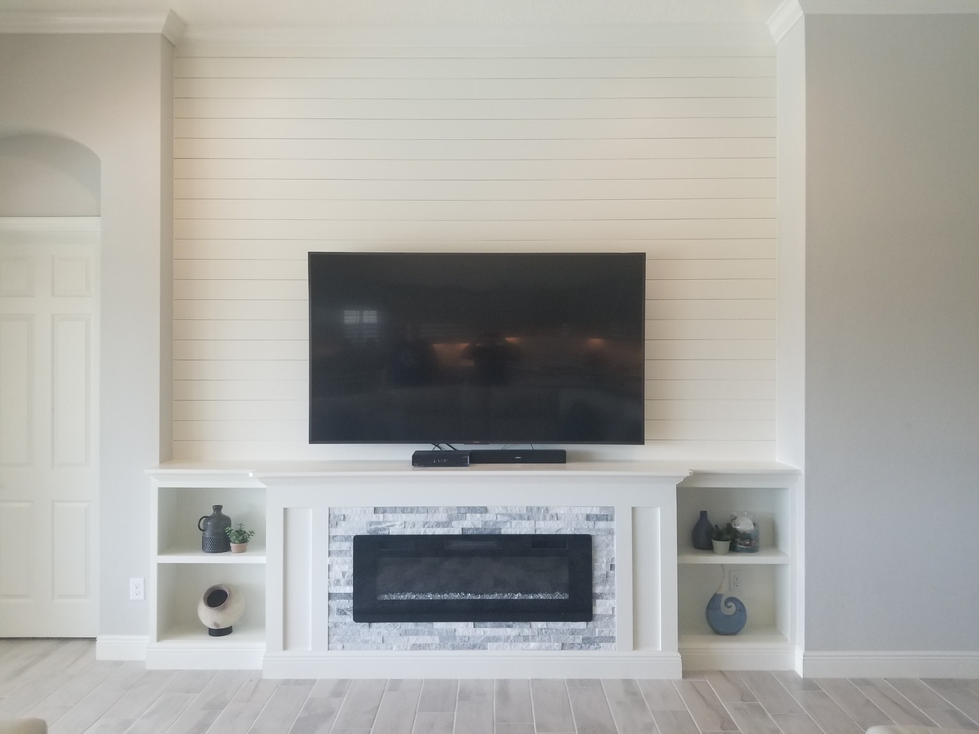 Shiplap entertainment center with stacked stone fireplace and shelves